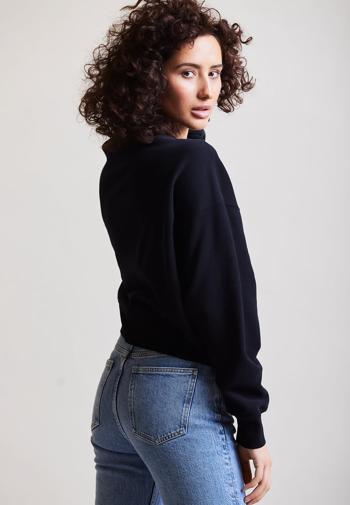 ["Black", " Model trägt Cropped Sweater in Schwarz Seitenansicht"]
