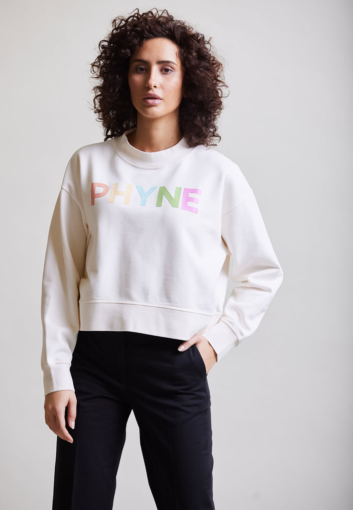 ["Model trägt Cropped Sweater mit PHYNE Print Vorderansicht"]