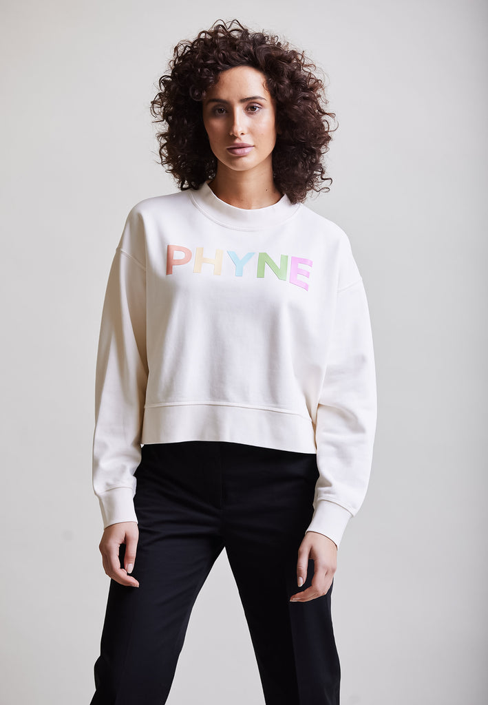 ["Model trägt Cropped Sweater mit PHYNE Print"]
