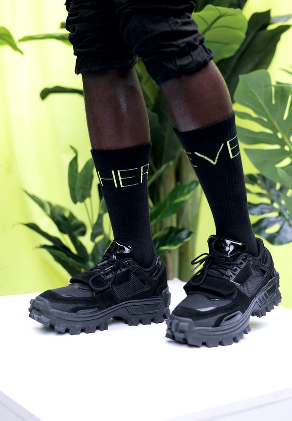 Model trägt Higher Level Tennis Socken in schwarz by Nikeata Thompson